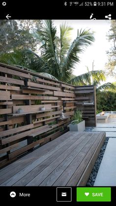 a wooden bench sitting next to a lush green forest filled with lots of greenery