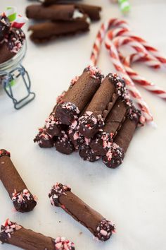 some candy canes and peppermink sticks on a white table with other candies