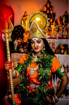 a woman dressed in an elaborate costume holding a stick