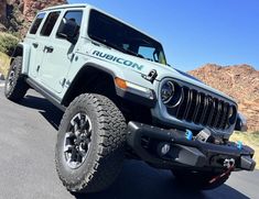 the jeep is parked on the side of the road in front of some mountains and rocks