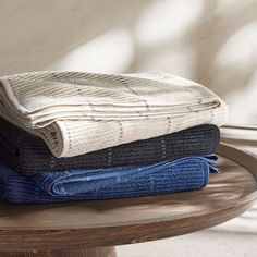 three folded blankets sitting on top of a wooden table