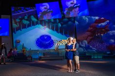 two people hugging each other in front of a large screen with cartoon images on it