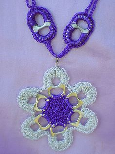 a purple and white crocheted necklace on a pink background