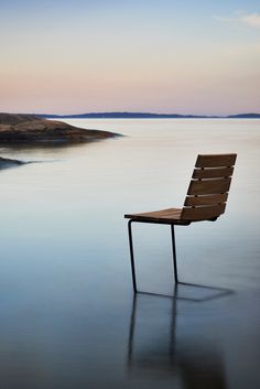 a wooden chair sitting on top of a body of water