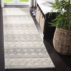 a large white rug in the middle of a living room next to a door and potted plant