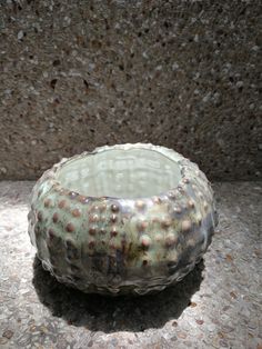 a ceramic bowl sitting on top of a stone floor next to a cement block wall