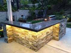 an outdoor bar made out of stone with lights on the top and outside area in the background