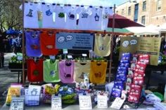 there are many t - shirts on display at this outdoor vendor's market stall