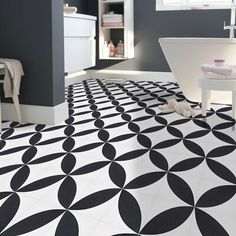 a bathroom with black and white tiles on the floor, toilet and sink in the background