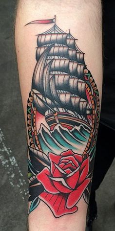 a man's arm with a ship and rose tattoo on it