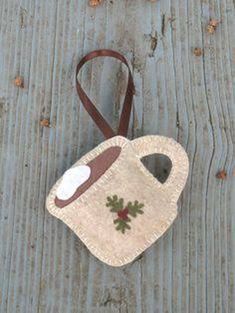 a small purse sitting on top of a wooden floor next to a string bag with holly decorations