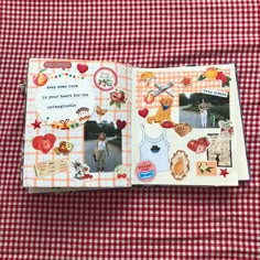 an open scrapbook with pictures and stickers on it sitting on a checkered table cloth