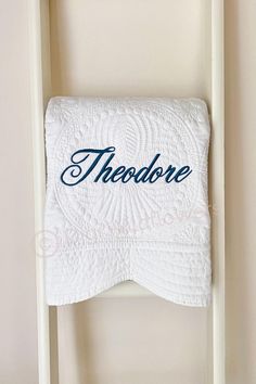 there is a white towel hanging on the wall with it's name in cursive writing