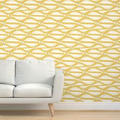 a white couch sitting in front of a wall with yellow and white designs on it