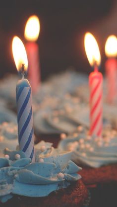 three cupcakes with lit candles on top of each one in front of some frosting