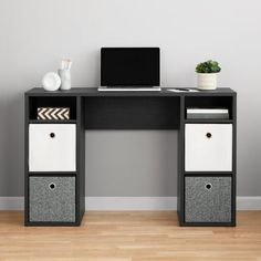 a computer desk with two drawers and a laptop on top of it, in front of a gray wall