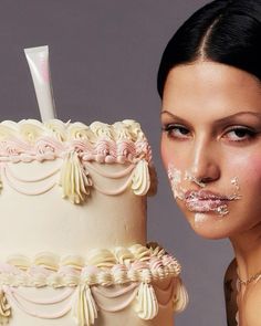 a woman is posing next to a cake with icing on her face and lip