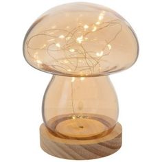 a mushroom shaped lamp with some lights on it's side and a wooden base