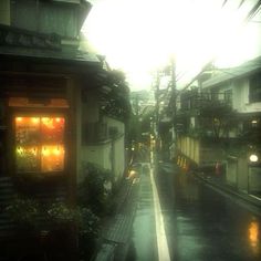 an alley way in the rain with buildings on both sides