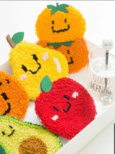 four crocheted apples and two oranges on a tray