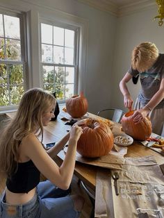 two people carving pumpkins on a wooden table