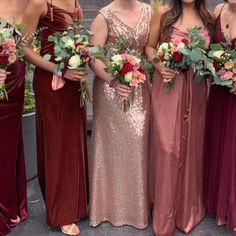 a group of women standing next to each other wearing dresses and holding bouquets in their hands