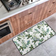 a kitchen area with a stove, oven and countertop covered in green leaves on a white rug