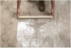 a person standing on the floor with a roll of clear plastic covering it's surface