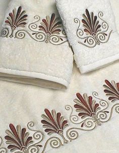 three towels with embroidered designs on them sitting next to each other