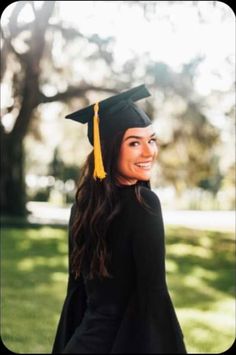 a woman wearing a graduation cap and gown standing in the grass with her hand on her hip