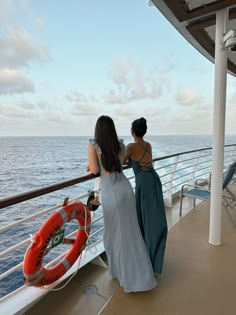 two women standing on the deck of a cruise ship looking out at the ocean and life preserver