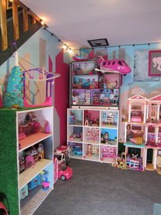 a room filled with lots of doll houses and toys on shelves next to a stair case