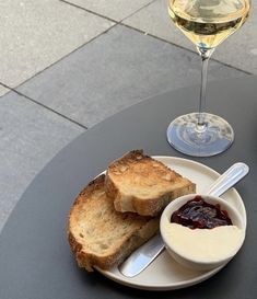 two slices of toast and jam on a plate with a glass of wine in the background