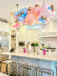 the balloons are hanging from the ceiling above the kitchen island and bar stools in front of it