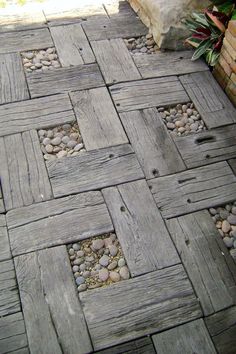 a wooden walkway with rocks and gravel in the center, next to a brick wall