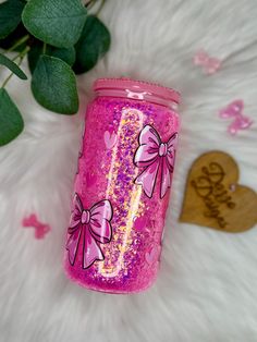 a pink tumbler sitting on top of a white fur covered floor