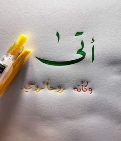 an arabic calligraphy written in green and orange ink with a yellow marker next to it