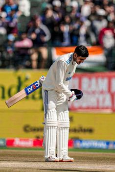 a man standing on top of a field holding a cricket bat