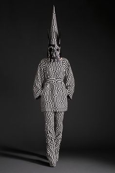 a black and white photo of a person in a weird suit with an odd hat