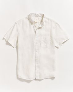 Our best-selling Tuscumbia shirt is the cornerstone of lived in luxury. This short-sleeve version is cut from lightweight linen that has been garment-dyed for an effortless, lived-in look and feel. It’s constructed in a standard fit and features a button-down collar, our signature notch pocket with double-needle stitching, and a box-pleated body. Thoughtfully finished with genuine mother-of-pearl buttons and a subtle detail: our heirloom ribbon applied to the bottom of the under placket. This sh White Button Up Men, White Linen Shirt Men, Groomsmen Outfits, Knit Swimwear, Billy Reid, Disney Bounding, Cap Fashion, White Button Up, Shirt Button