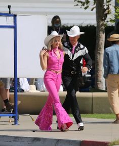 a man and woman in cowboy hats walking down the street