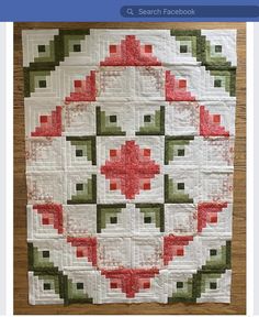 a close up of a quilt on a wooden table with a white and red design