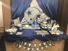 a football themed dessert table is set up with blue and white decorations, including an american football helmet