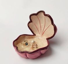 a pink shell shaped box with two rings in it