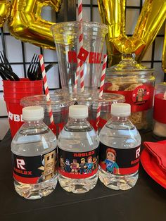 three bottles of water sitting next to each other on a table with balloons in the background