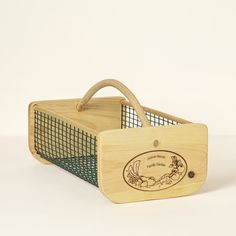 a wooden basket that has a handle on the front and sides, with a green net around it