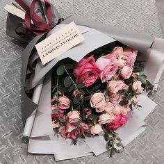 a bouquet of pink roses is wrapped in gray paper