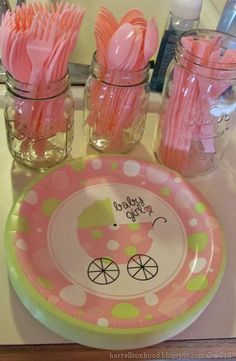 pink and green baby shower party supplies on a bathroom counter with mason jars filled with toothbrushes