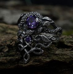 Handcrafted for enchanting souls, our ethereal fairy witchy wedding ring set embodies mystical allure and magical elegance. Crafted from sterling silver, it features intricate details inspired by celtic fantasy, including delicate branches and leaves, complemented by a striking dragon motif. The enchanting purple hue adds a touch of magic to this silver witches knot jewelry, making it a perfect choice for those seeking a unique and mystical accessory set for their special day. Characteristics: Metal - Recycled solid sterling silver  Stone - Cubic Zirconia Finish - Oxidized. View all silver dragon rings: https://www.etsy.com/shop/TinyShinyJewel?ref=seller-platform-mcnav&section_id=45210616 Care instructions: To care for the ring, avoid contact with water and chemicals such as perfumes and l Sterling Silver Fantasy Ring, Gothic Gemstone Wedding Ring, Gothic Wedding Gemstone Ring, Sterling Silver Magical Promise Ring, Gothic Wedding Ring With Gemstone, Silver Fantasy Promise Ring, Fantasy Sterling Silver Ring, Dragon Wedding Ring, Nature-inspired Silver Amethyst Jewelry