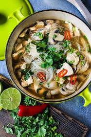 an overhead view of a bowl of chicken noodle soup with cilantro and lime